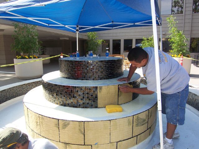 man installing glazed tile in pond